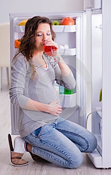 Pregnant woman near fridge looking for food and snacks