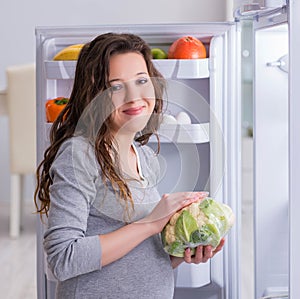 Pregnant woman near fridge looking for food and snacks