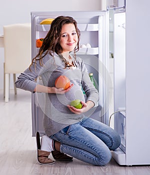 Pregnant woman near fridge looking for food and snacks