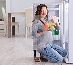 Pregnant woman near fridge looking for food and snacks