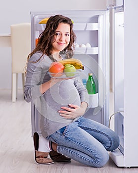 Pregnant woman near fridge looking for food and snacks