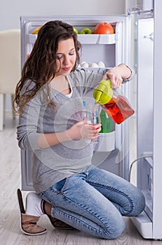 Pregnant woman near fridge looking for food and snacks