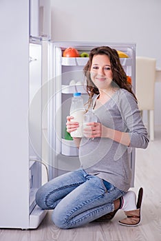 The pregnant woman near fridge looking for food and snacks