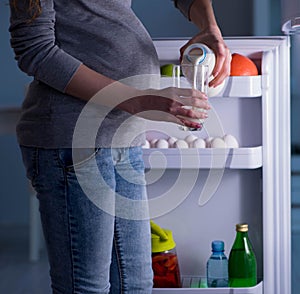 Pregnant woman near fridge looking for food and snacks at night