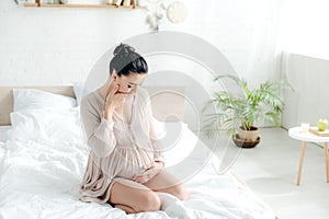 Pregnant woman in nightie having nausea in bedroom