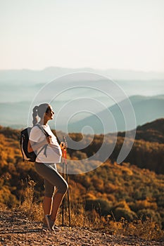 Pregnant woman nordic walking with trekking poles with beautiful autumn view