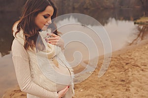 Pregnant woman on outdoor autumn walk, cozy warm mood