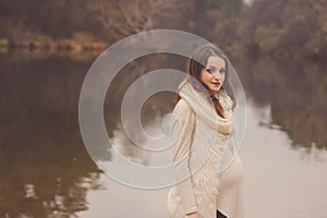 Pregnant woman on outdoor autumn walk, cozy warm mood