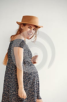Pregnant woman over white background posing in studio. Beautiful pregnant woman with long hair in a summer dress on a
