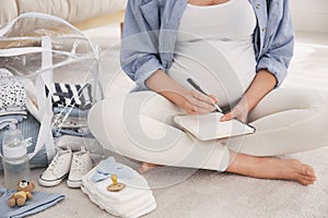 Pregnant woman packing bag for maternity hospital at home, closeup