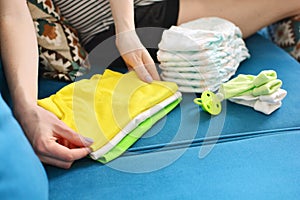 Pregnant woman packing bag for maternity hospital at home. Expectant mother folds clothes for a newborn