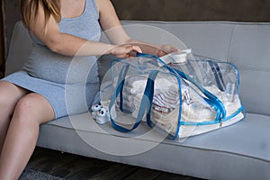 Pregnant woman packing bag for maternity hospital at home. pregnancy, childbirth and people