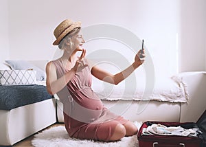 Pregnant woman packing suitcase for hospital or journey, getting ready for newborn baby, labor, making list or taking photo with