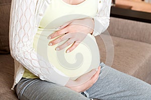 Pregnant woman with painful belly on sofa at home