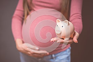 Pregnant woman with piggy bank, saving money to her newborn baby.