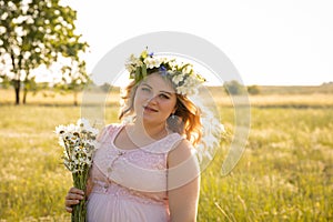 A pregnant woman in a pink dress walks in nature