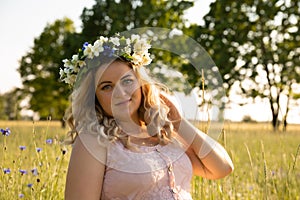 A pregnant woman in a pink dress walks in nature