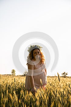 A pregnant woman in a pink dress walks in nature