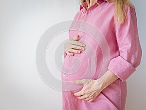 pregnant woman in a pink shirt stands on a white background
