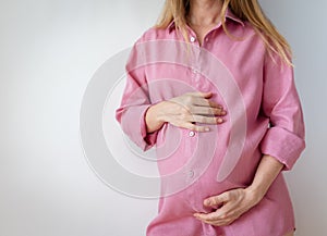 a pregnant woman in a pink shirt stands on a white background