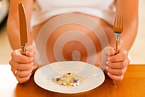 Pregnant woman with plate full of pills