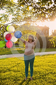 A pregnant woman playing with ballons