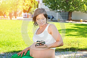 Pregnant Woman playing with little baby boy shoes
