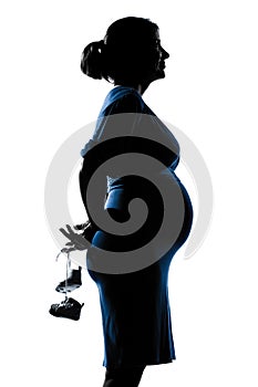 Pregnant woman portrait holding baby shoes