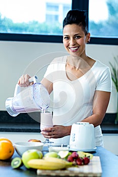 Pregnant woman pouring smoothie in glass