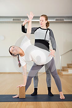 Pregnant woman practices yoga with an instructor. Extended Side Angle Pose or Parivrtta Parsvakonasana