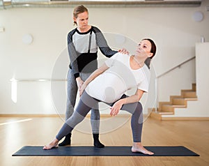 Pregnant woman practices yoga with an instructor. Extended Side Angle Pose or Utthita Parsvakonasana