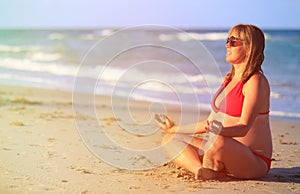 Pregnant woman practicing yoga at beach