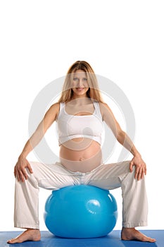 Pregnant woman practicing yoga with blue ball