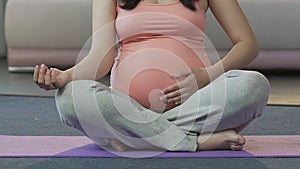 Pregnant woman practicing yoga on floor, prenatal exercising, physical activity