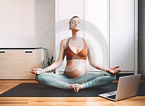 Pregnant woman practicing yoga online at home with laptop