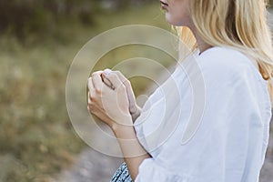 Pregnant woman praying outdoors on at sunset. Concept for faith, spirituality and religion.