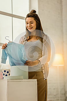 Pregnant woman preparing clothes for her future baby