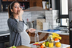 Pregnant woman preparing healthy food with lots of fruit and vegetables at home