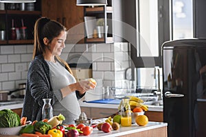 Pregnant woman preparing healthy food with lots of fruit and vegetables at home