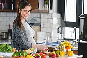 Pregnant woman preparing healthy food with lots of fruit and vegetables at home