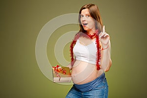 Pregnant woman with the present, thinking what to give a baby or relatives on Christmas.