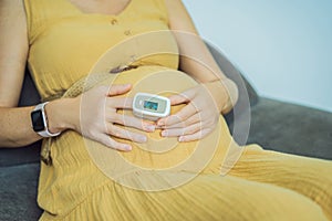 Pregnant woman with pulse oximeter on finger. Doctor measuring oxygen saturation level while visiting expectant mother