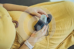 Pregnant woman with pulse oximeter on finger. Doctor measuring oxygen saturation level while visiting expectant mother