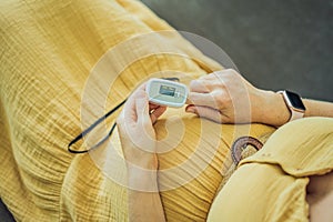 Pregnant woman with pulse oximeter on finger. Doctor measuring oxygen saturation level while visiting expectant mother