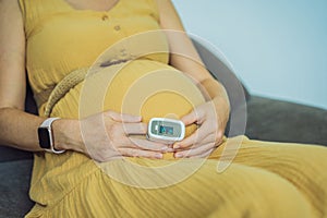 Pregnant woman with pulse oximeter on finger. Doctor measuring oxygen saturation level while visiting expectant mother