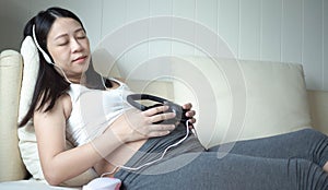 A pregnant woman put the headphone into her stomach, to open the music for fetus listen.