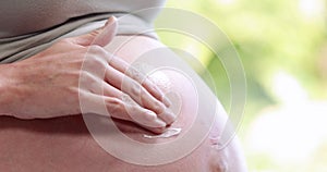 Pregnant woman putting lotion on belly