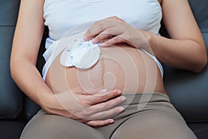 Pregnant woman putting small shoes for the unborn baby on the belly