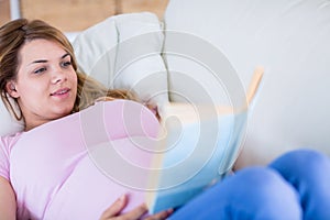 Pregnant woman reading a book on couch