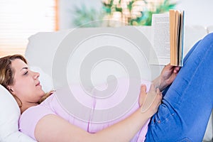 Pregnant woman reading a book on couch